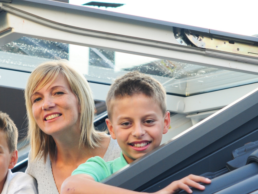 Kinder und Mutter schauen aus Dachfenster